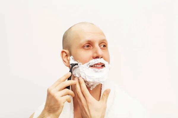 英俊男子用剃须刀刮胡子并向别处看的画像 — 图库照片