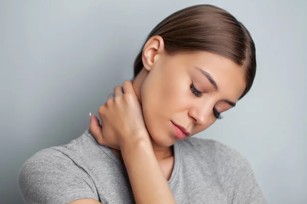 Mujer joven que experimenta dolor severo en el cuello mientras sostiene sus manos —  Fotos de Stock