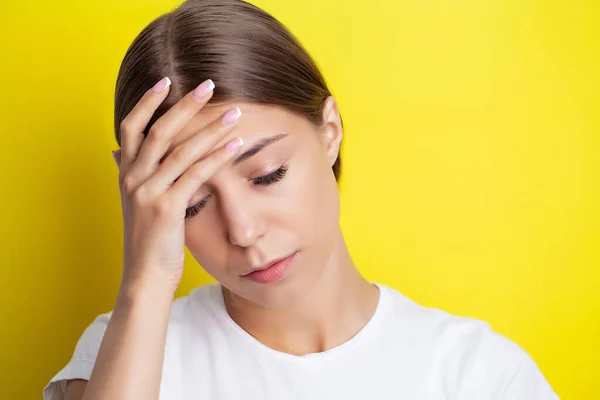 Una giovane donna tiene la mano vicino alla testa e sente un forte mal di testa — Foto Stock