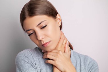 Genç bir kadın ellerini tutarken şiddetli boyun ağrısı çekiyor.