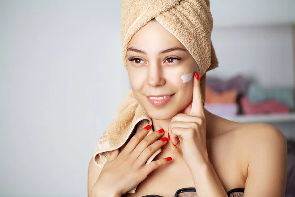 Huidverzorging concept, portret van een vrolijke vrouw die cosmetische crème op het gezicht aanbrengt. — Stockfoto