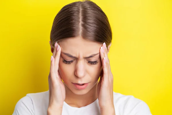 Een jonge vrouw houdt haar hand tegen haar hoofd en voelt een ernstige hoofdpijn — Stockfoto