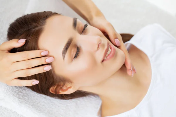 Young pretty woman enjoying face massage procedure