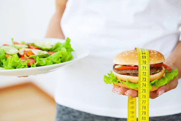 Harmful food, fat burger next to the yellow measuring tape