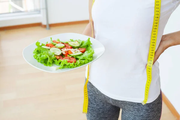 Comida de dieta, closeup de salada fresca em um boliche e fita métrica amarela — Fotografia de Stock