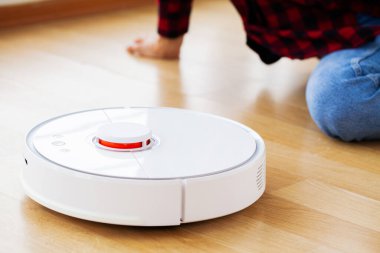 Kadın akıllı robot elektrik süpürgesini çalıştırıyor.