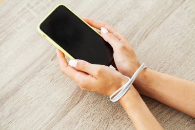 Kabloyla akıllı telefon aygıtına bağlanmış kadın ellerinin üst görüntüsünü kapat