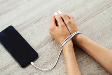Kabloyla akıllı telefon aygıtına bağlanmış kadın ellerinin üst görüntüsünü kapat