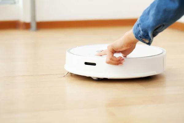 Close up of woman turns on smart robot vacuum cleaner