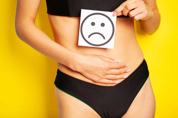 Salud de la mujer, cuerpo femenino sosteniendo triste sonrisa tarjeta cerca del estómago. — Foto de Stock