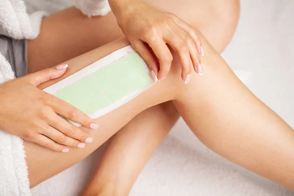 Waxing woman leg with wax strip at beauty spa — Stock Photo, Image