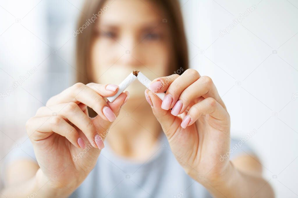 Stop smoking, young girl holding broken cigarette in hands.