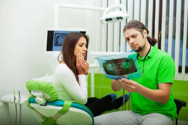 Dentista em consultório odontológico conversando com paciente do sexo feminino e se preparando para o tratamento — Fotografia de Stock