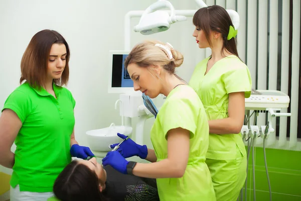 O dentista está a tratar dos dentes ao cliente no consultório dentário. — Fotografia de Stock