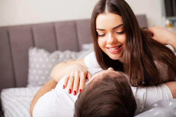 Pareja feliz divirtiéndose en la cama. Íntima sensual joven pareja en el dormitorio disfrutando el uno del otro —  Fotos de Stock