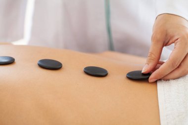 Sıcak taşlarla masaj yaptıran bir kadın.