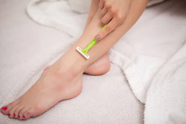 A nő borotvát használ a gyönyörű lábain. — Stock Fotó
