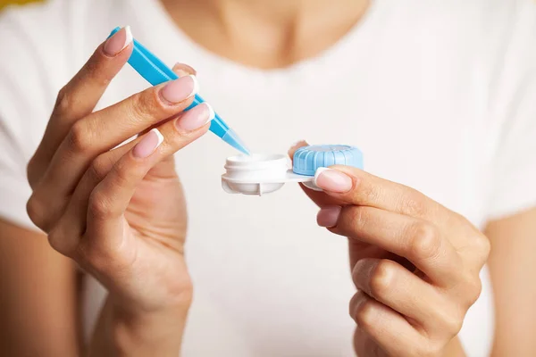 Close up of woman get contact lenses out of container with liquid