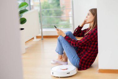 Kadın akıllı robot elektrik süpürgesini açıyor.