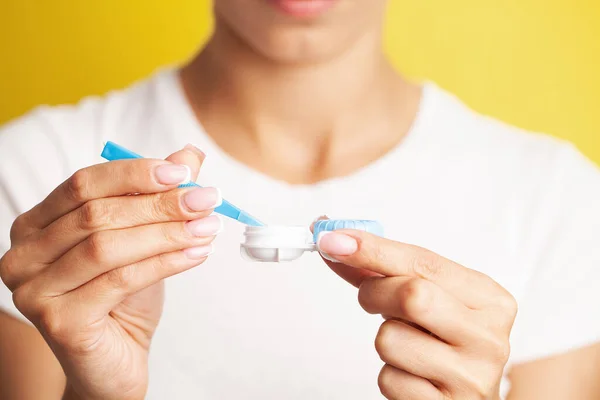 Close up of woman get contact lenses out of container with liquid