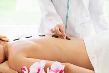 Sıcak taşlarla masaj yaptıran bir kadın.