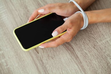 Kabloyla akıllı telefon aygıtına bağlanmış kadın ellerinin üst görüntüsünü kapat