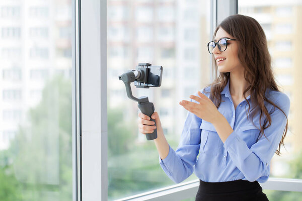 Молодая деловая женщина записывает видео блог на смартфоне в офисе компании