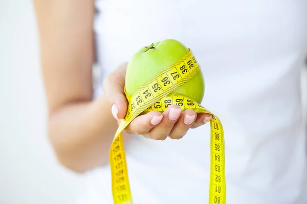 Ernährungskonzept: Frau hält einen Apfel mit Maßband herum — Stockfoto