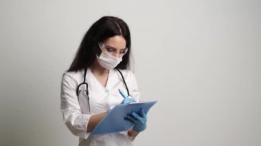 Maskeli ve eldivenli doktor hastalara bal kartı doldurur.