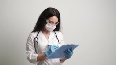 Maskeli ve eldivenli doktor hastalara bal kartı doldurur.