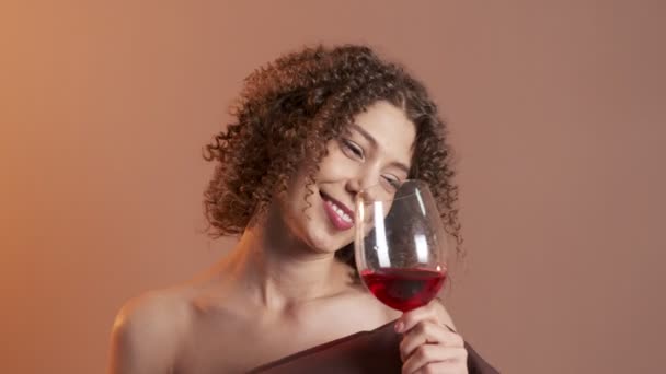 Beautiful woman with a glass of red wine and a pillow instead of a dress — Stock Video