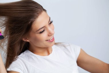 Genç bir kadın banyodaki saçlara yağ sürüyor.