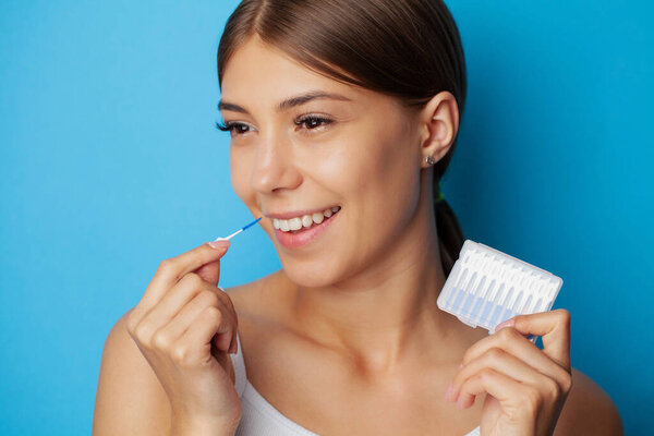 The woman uses brushes to clean the interdental spaces