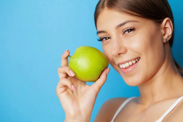 완전 한 미소를 가진 명랑 한 젊은 여자가 녹색 사과를 먹는 모습 — 스톡 사진