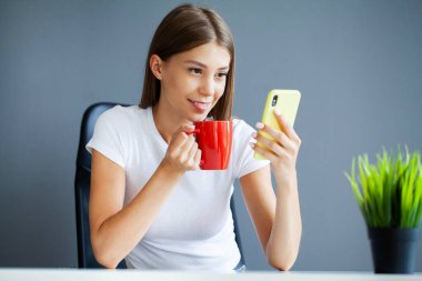 Akıllı telefon tutan, mesaj yazan, sosyal ağlarda arkadaşlarıyla sohbet eden bir kadın.