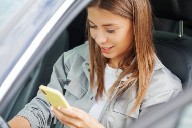 Akıllı telefon tutan, mesaj yazan, sosyal ağlarda arkadaşlarıyla sohbet eden bir kadın.