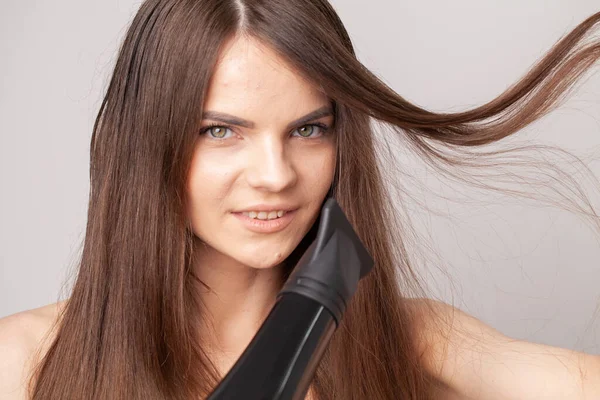 Schöne lächelnde Mädchen mit blonden langen glatten Haaren mit Haartrockner. — Stockfoto