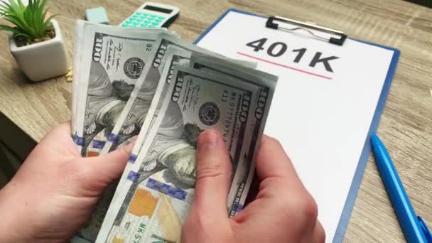 401k pensioen plan, een man telt 100 dollar biljetten aan een houten tafel. — Stockvideo