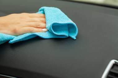 Arabanın içini mavi bir paçavrayla silen kadına yakın plan.