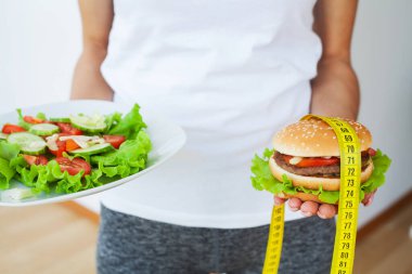 Diyet konsepti, abur cubur ve taze salata arasında seçim yapan kadın.