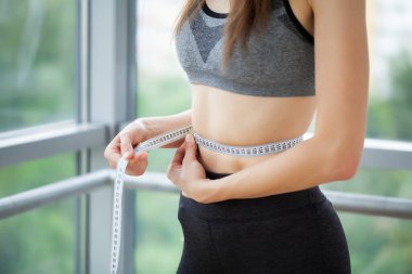 İnce bir kadın, belinin büyüklüğünü ölçer..
