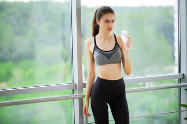 Spor salonunda dans ederken su içen sağlıklı genç bir kadının portresi..