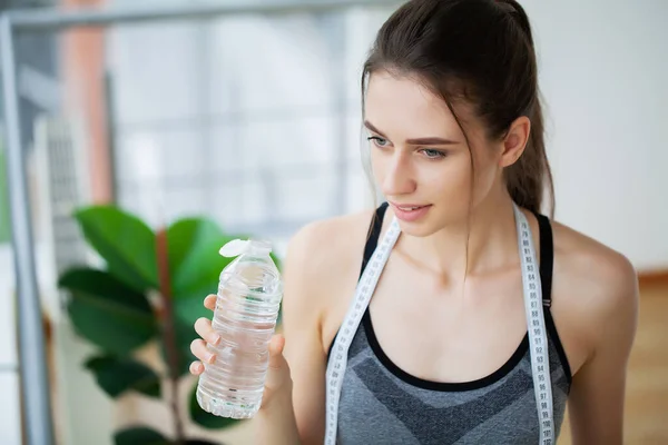 Портрет молодой женщины пригодной питьевой воды во время тренировки в тренажерном зале. — стоковое фото