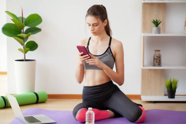 Bayan ideal ağırlığı ve fiziksel biçimi korumak için evde dizüstü bilgisayarın önünde egzersiz yapıyor.