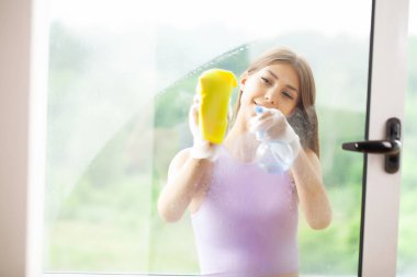 Genç Gülümseyen Kadın Süngerle Pencereyi Siliyor