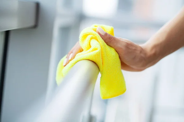 Professional cleaning lady cleans table using a sponge and spray