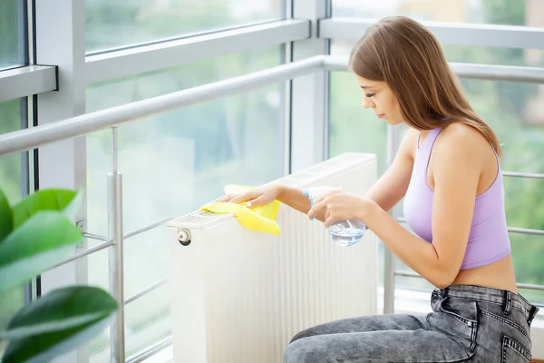 직업적으로 청소를 하는 여자가 스폰지와 스프레이를 사용하여 식탁을 청소 한다 — 스톡 사진