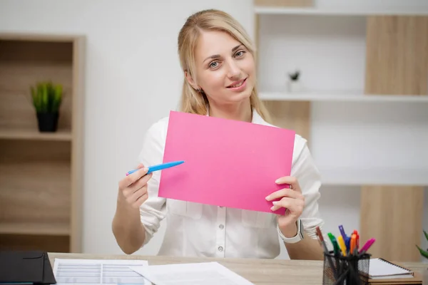 Biznes kobieta siedzi przy biurku trzymając pusty papier — Zdjęcie stockowe