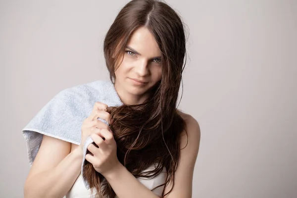 Young woman drying her hair with towel on light background — Stock Photo, Image