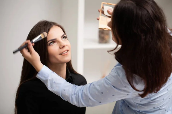 Professionelle Maskenbildnerin arbeitet mit schöner junger Frau — Stockfoto